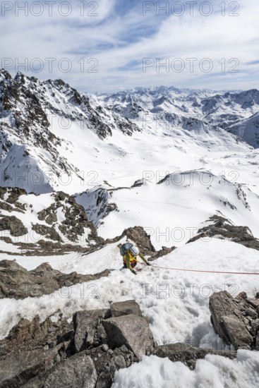 Mountaineer climbing up a steep snow slope, secured by a rope, ascent to the summit of Piz Grialetsch in winter, view of mountain panorama with Piz Vadret with snow, Grisons Haute Route, Albula Alps, Rhaetian Alps, Grisons, Switzerland