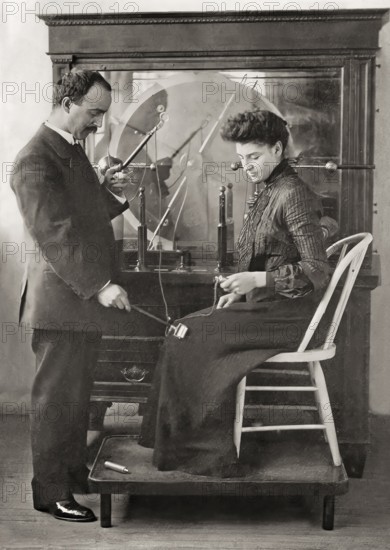 A patient being treated by Proffessor Wilhelm Conrad Röntgen with a friction spark treatment, an early electric medical Electro-Therapeutics