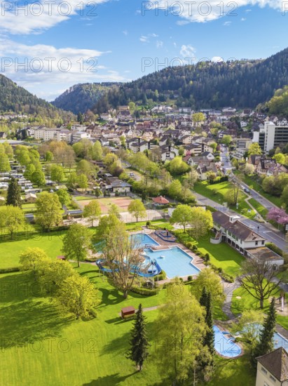 Overview of park with outdoor pool and town in the background in mountainous surroundings, Bad Liebenzell, district of Calw, Black Forest, Germany