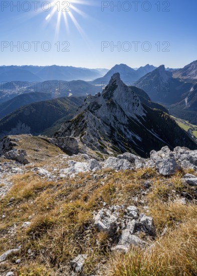 View at the summit of the Große Arnspitze, mountain panorama with Leutasch valley and Arnplattenspitze, sun star, autumnal mountain landscape, near Scharnitz, Bavaria, Germany