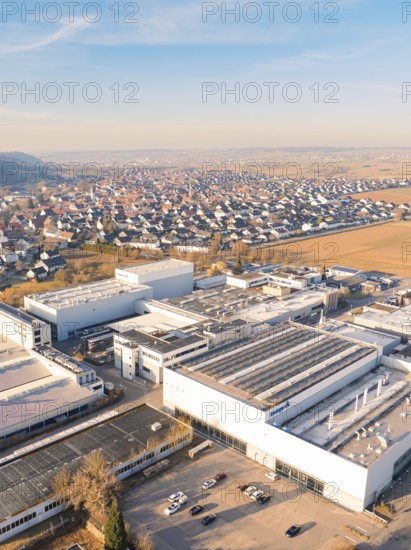 Aerial view of industrial plants next to a settlement under a blue sky in a rural setting, Nufringen, Germany