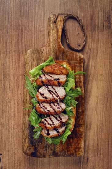 Sandwich with duck breast and arugula, balsamic sauce, on a wooden chopping board, breakfast, homemade, without people