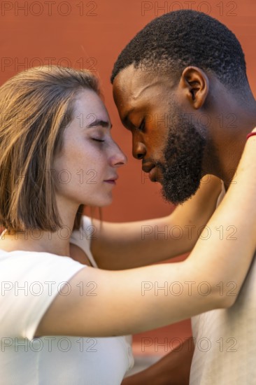 Vertical photo of a young multi-ethnic couple sharing a romantic moment embracing face to face