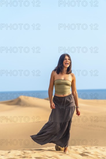 Young woman enjoying a sunny day walking on the maspalomas dunes in gran canaria, spain, expressing happiness and freedom