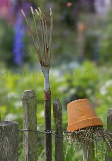Nesting aid for earwigs, insects, clay pot with straw, rake on a wooden garden fence, Münsterland, North Rhine-Westphalia, Germany