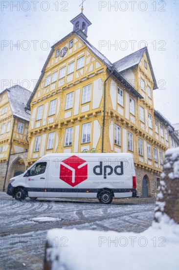 A DPD delivery van stands in front of a yellow-painted half-timbered building covered in snow, Sindelfingen, Germany