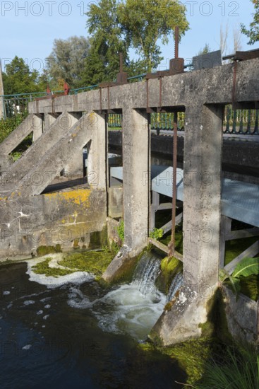 An old lock structure with concrete and masonry over which water flows, surrounded by trees, Cléry-sur-Somme, Cléry-su-Sonme, River Somme, Péronne, Hauts-de-France, France