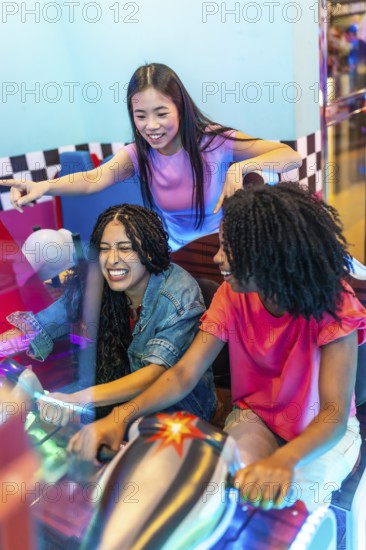 Group of female friends enjoying a lively gaming session, laughing and competing in a racing game at an exciting entertainment venue