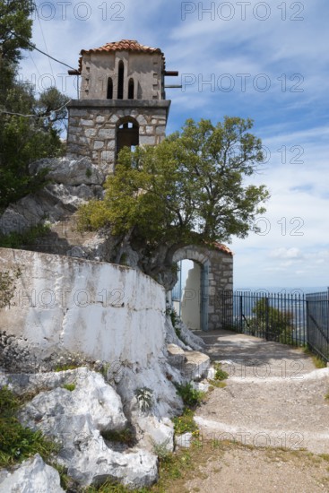 An old stone tower stands by the wayside under a clear blue sky, rock church of Smerna, Church of the Assumption of the Virgin Mary, Panagia Smerniotissa, Elis, Peloponnese, Greece