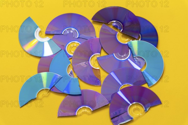 Top view of cut CDs and DVDs against a yellow background