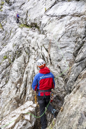 Mountain rescuers from Bergwacht Bayern climbing a steep rock face on Hoher Göll, Berchtesgaden, Berchtesgadener Land, Upper Bavaria, Bavaria, Germany