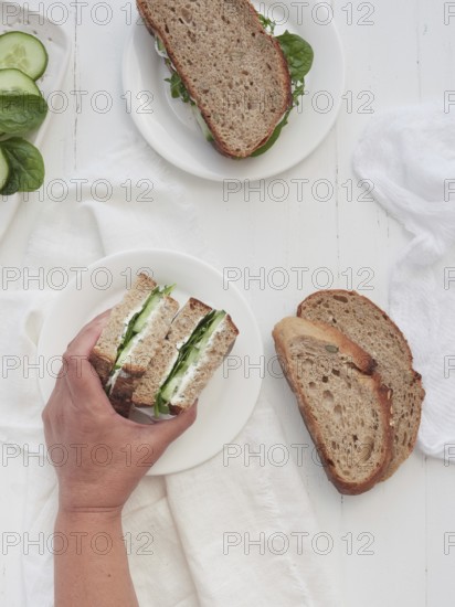 Hand picking from a platter of cucumber and spinach vegetarian sandwich