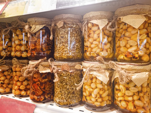 Jars of honey filled, with various nuts and seeds, are displayed on the store shelf, no people, mobile photo