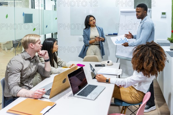 Diverse marketing team analyzing growth charts during a productive meeting in a modern coworking office