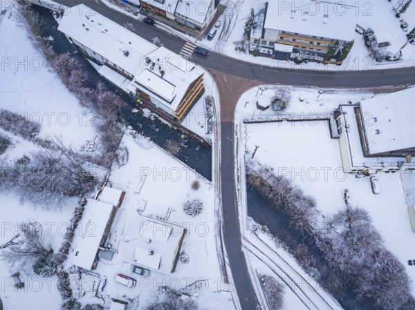 Snowy street view with river and crossing bridge, Enzklösterle, district of Calw, Black Forest, Germany