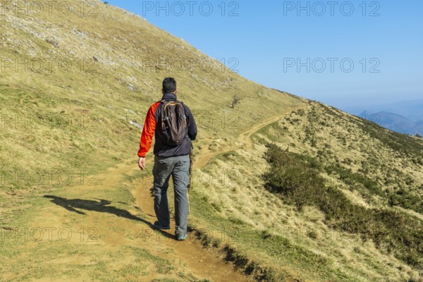 A man descending from the summit of Mount Ernio or Hernio in Gipuzkoa at sunset, Basque Country