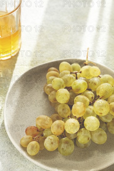 A branch of white grapes, on a gray plate, with a glass of white wine, top view, natural light, food concept, no people