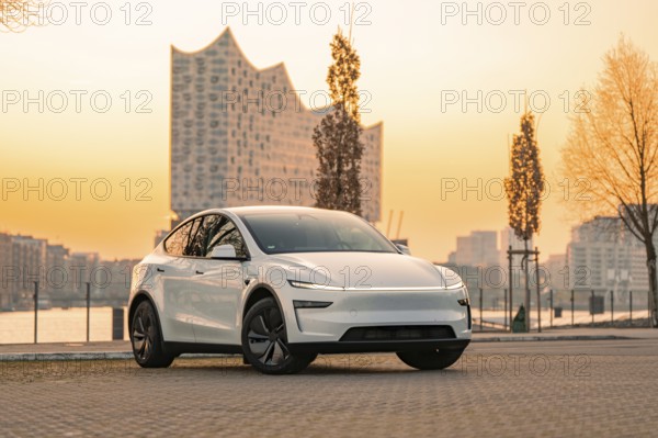 White electric car in front of a modern building at sunset in the city, Tesla New Model Y, Germany