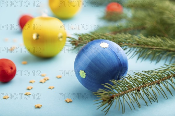 Christmas or New Year composition. Decorations, blue, red, yellow balls, fir and spruce branches, on a blue paper background. Side view, close up, selective focus