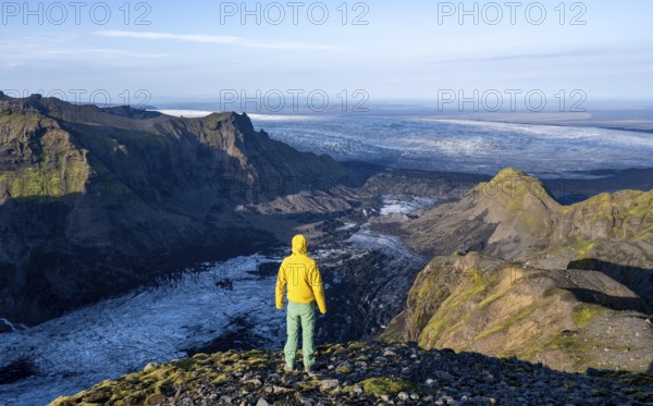 Young man, tourist in front of impressive landscape with glacier in the evening light, glacier tongues Huldujökull and Kötlujökull, Myrdalsjökull glacier, Pakgil, Iceland