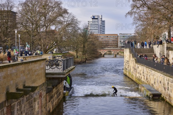 Leine wave, river Leine, footpath, bare wintry trees, lanterns, general architecture, high-rise building, artificial wave, wave surfing, pedestrians as accessories, diffuse light, milky blue cloudy sky, slightly sunny, Am Hohen Ufer, Leibnizufer, Mike-Gehrke-Promenade, Hanover, state capital, Hanover region, Lower Saxony, Germany