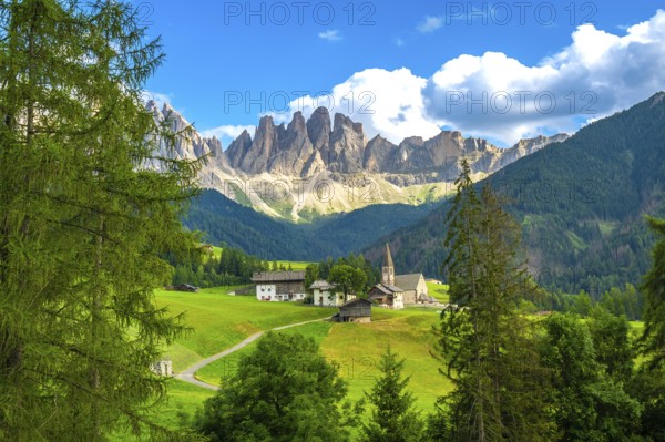 Scenic landscape showing st. Magdalena church in val di funes with the odle mountain range in the background during a sunny summer day