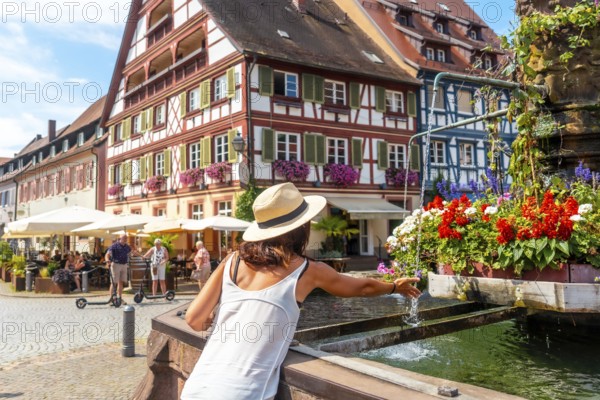 A female tourist cooling off in the fountain in summer in the old town of Gengenbach in the Black Forest, Germany
