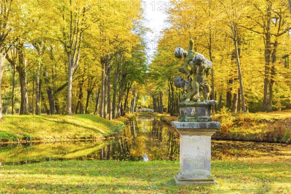 Group of figures in the park of Hermsdorf Castle with castle moat in autumn, Ottendorf-Ockrilla, Saxony, Germany