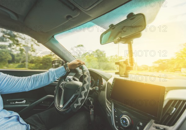 Interior view of a man driving a car. Driver hands on the steering wheel