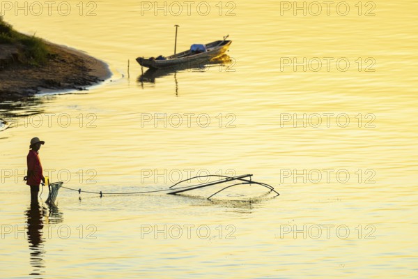 Fisherman with a sinking net at sunset on the Mekong, Luang Prabang, Laos