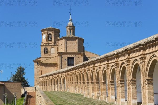 Historisches Backsteingebäude mit Bögen und einem Uhrturm unter blauem Himmel, Basílica de Nuestra Señora del Romero, Basilika Unserer Lieben Frau von Romero, Cascante, Navarra, Spanien