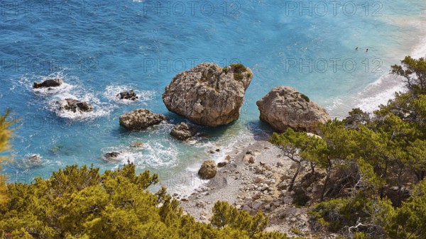 Large rocks in the turquoise sea on a coast overgrown with pine trees, Kato Lakkos Beach, still almost unspoilt bay, not accessible by car, Kato Lakkos, east coast, Karpathos, Dodecanese, Greek Islands, Greece