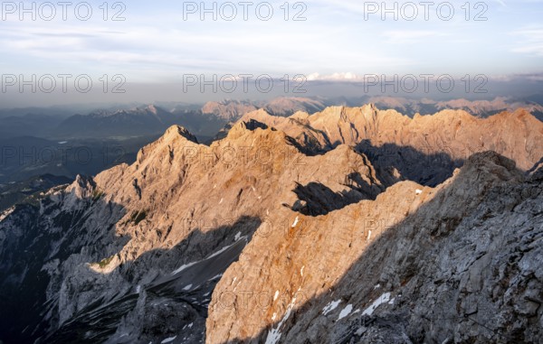 Impressive rocky mountain landscape, steep mountain ridge, Jubiläumsgrat with Alpspitze, mountain panorama from the summit of the Zugspitze, alpenglow at sunset, Northern Limestone Alps, Wetterstein Mountains, Bavaria, Germany