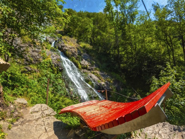 Red seat under the Todtnau waterfall in the Black Forest in Germany in a beautiful landscape