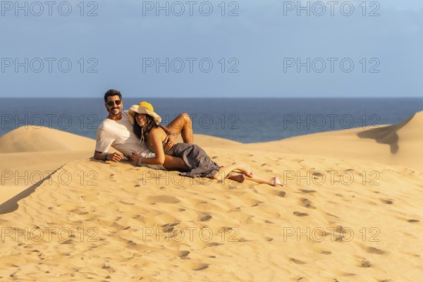 Couple relaxing on the warm sand of maspalomas dunes, enjoying the stunning ocean view and creating lasting memories together
