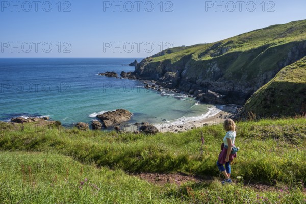 A hiker on a coastal path. View of Rose-an Hale Cove. Between Gurnard's Head and Carnelloe Headland. Cornwall, England, Great Britain