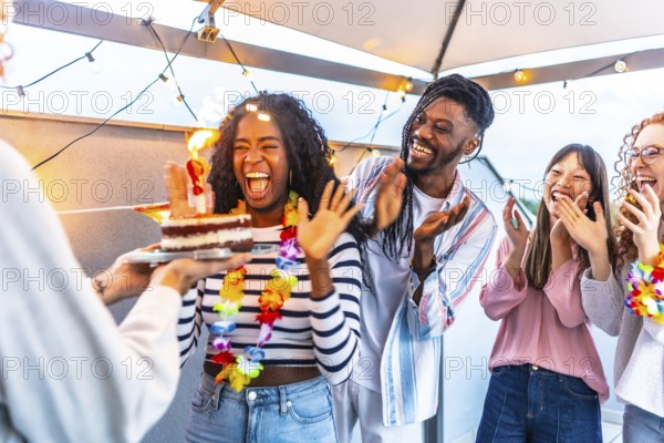 African woman celebrating her birthday with her multiracial friends during sunset in a terrace