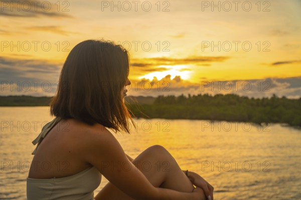 Young woman enjoying a peaceful golden sunset over the tropical landscape of siargao island, philippines, from the afam bridge