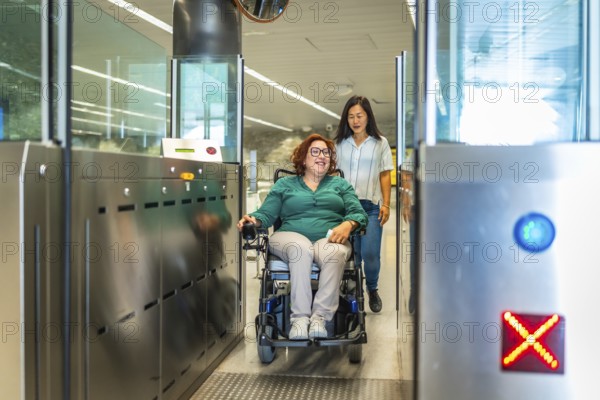 Smiling caucasian adult disabled woman in a wheelchair and chinese caregiver exiting the metro doors
