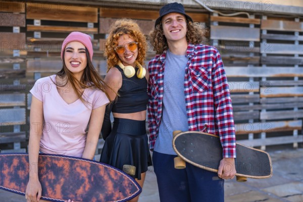 Group of cheerful friends enjoying time at skateboarding park. Female and male skaters standing with boards, expressing positive urban lifestyle