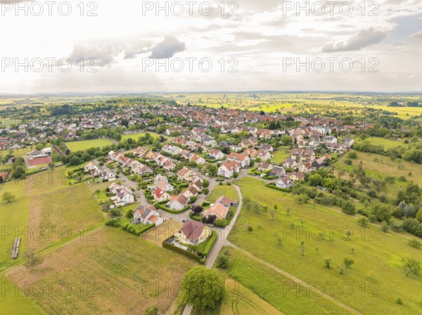 Overview of a residential area with many houses and streets, surrounded by wide fields under a slightly cloudy sky, Kieselbronn, Germany