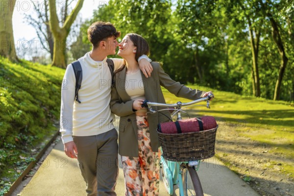 Romantic couple sharing a tender kiss while strolling through a park with their bicycle, enjoying a leisurely afternoon together