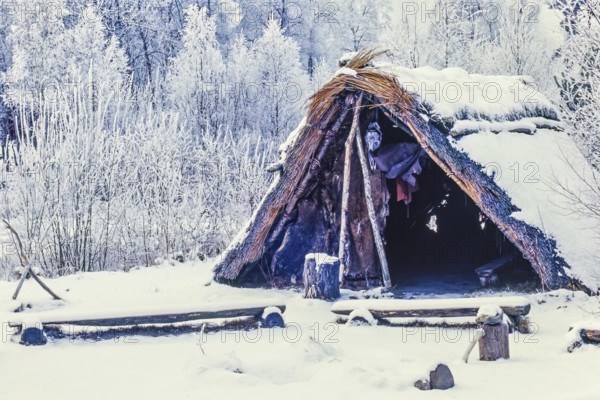Reconstruction of a Stone Age settlement with a grass hut with snow and frost a cold winter day, Åsarp, Falköping, Sweden