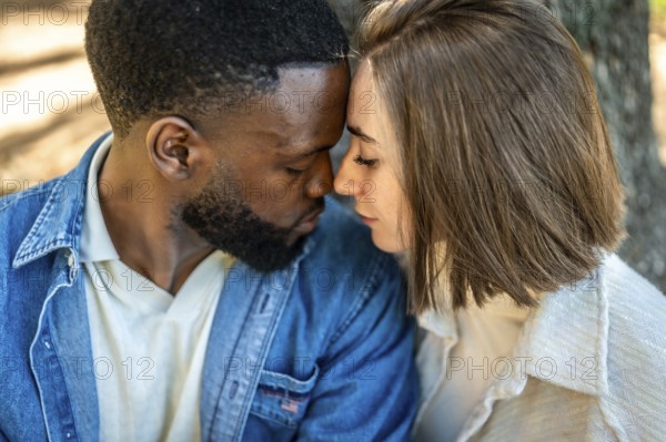 Close up of a beautiful Mixed-race young couple enjoying each other rubbing roses and embracing in a park