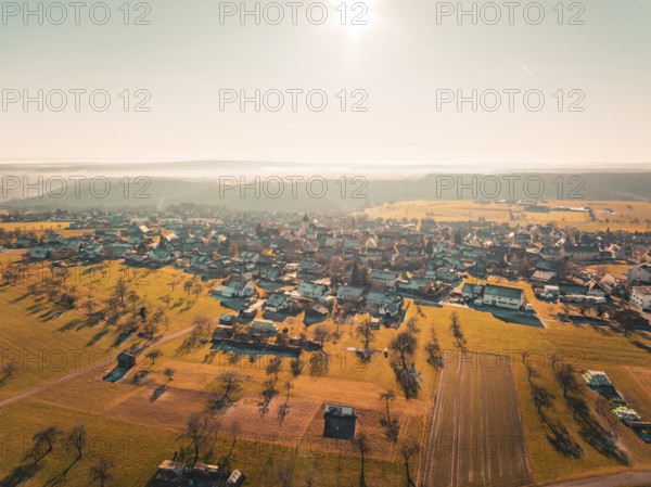 View of a village surrounded by fields and trees in the warm autumn light, Neubulach, Black Forest, Germany