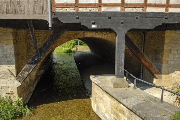 View from the Rathausbrücke bridge onto an arch of the Krämerbrücke bridge with the Gera river flowing through it in the historic city centre of Erfurt, Thuringia, Germany