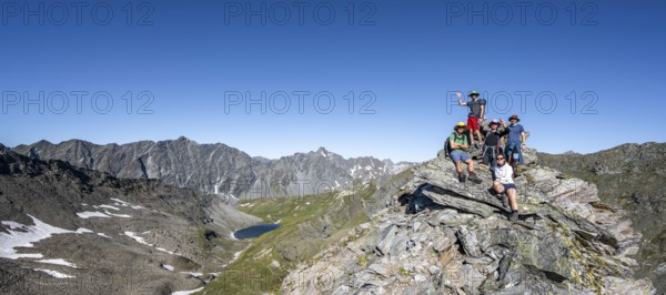 Group of mountaineers on the summit of the Göseleswand, mountain landscape with rocky mountain peaks, view of mountain basin with mountain lake Bödensee and Panargenkamm, Lasörlinggruppe, Hohe Tauern National Park, East Tyrol, Tyrol, Austria