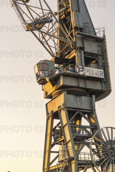 Old harbour crane in warm evening light, industrial charm and robust metal, Hamburg, Germany