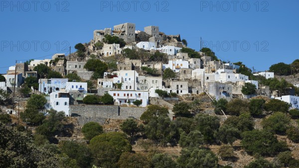 A hill with white houses, partly dilapidated ruins and Mediterranean vegetation under a blue sky, Emporio village, Volcanic Island, Nisyros, Dodecanese, Greek Islands, Greece