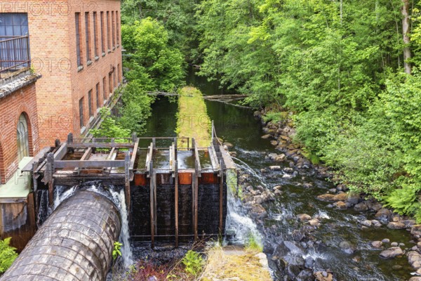 Old hydroelectric plant in a small river with a water tube in wood and a brick building, Ryfors, Mullsjö, Sweden